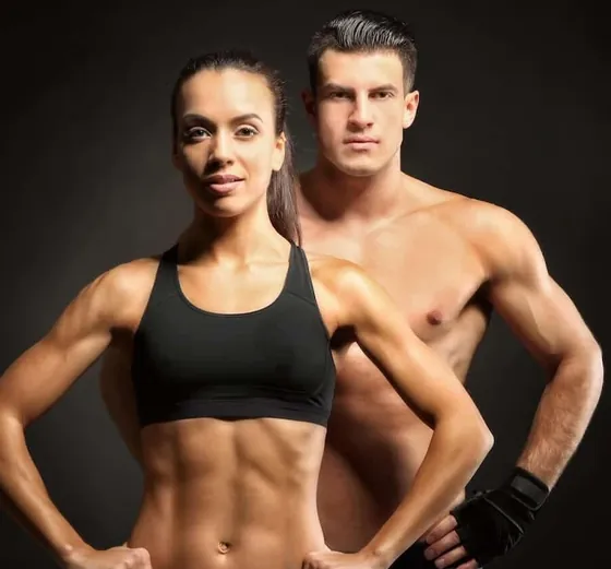 Fit man and woman in workout clothes posing in a studio