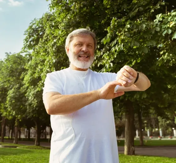 Older man checking his watch on a morning walk in a park